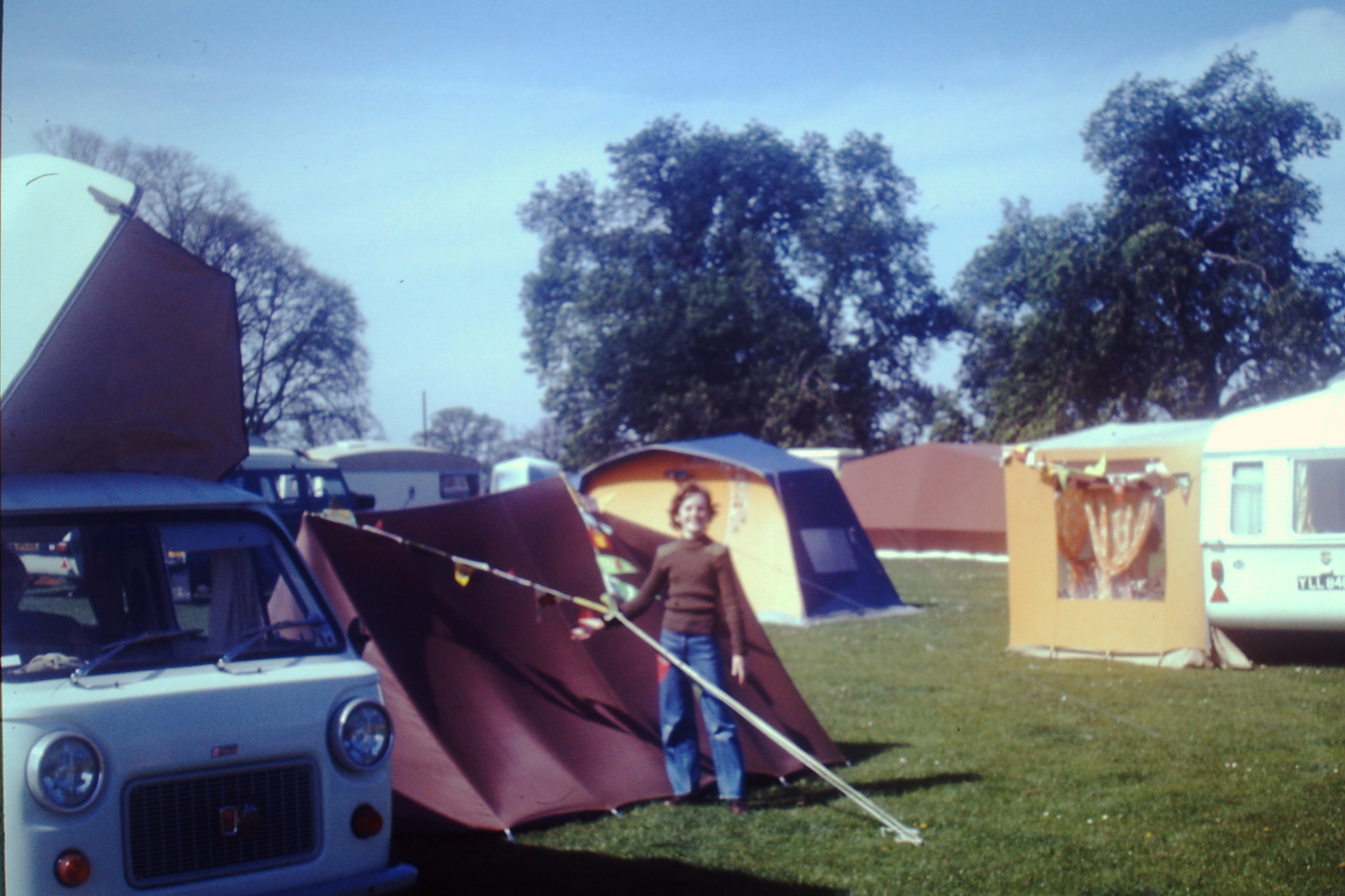 Old photo of a young girl standing beside an old-fashioned brown ridge tent