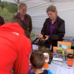 Two members of the ARC team showing a family a smooth snake.