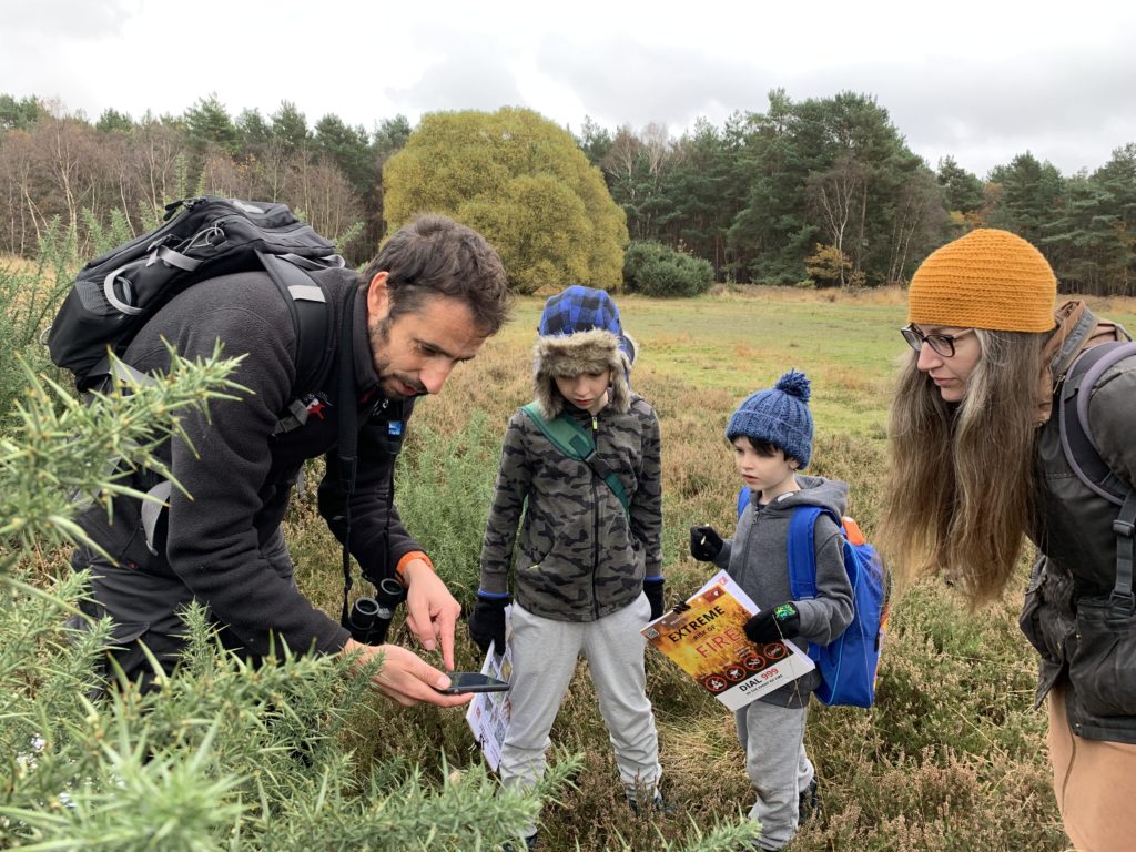 Photo of a family learning about heathland - two small boys looking intrigued at something Michael is showing them