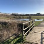 Photo of a wooden footbridge and meadows beyond