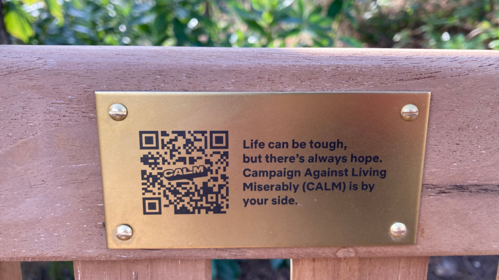 Brass plaque reads "Life can be tough, but there's always hope. Campaign Against Living Miserably (CALM) is by your side."