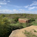 Photo of two hilltop pillboxes with a wide view beyond.