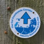 Photo of the blue waymarkers used to mark the route, with blue arrow and blue text "The Cut Countryside Corridor".