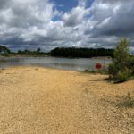 Photo of a gravelly 'beach' by a desolate looking pond.