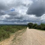 Photo of a wide gravel track, with dramatic clouds behind.