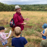 Photo of Warden Mike looking for butterflies with a group of children.