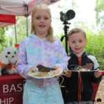 Photo of a little girl and alittle boy proudly holding the Nightjar nests they've made