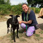 Photo of smiling lady with a black whippet.