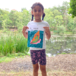 Photo of a young girl holding up her reptile colouring sheet.