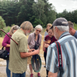 Photo of Andrew holding his insect net, with a crowd of interested people looking on.