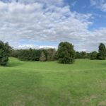 Panoramic photo of a landscaped park with mature trees.