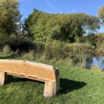 Photograph of a bench looking out across a pond.