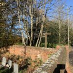 Photo of the corner of the churchyard where a finger post marks the route.