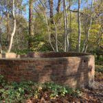 Autumnal photo of a circular brick-built structure in woodland.