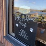 Photo of a sign in the café window saying "Dogs welcome inside".