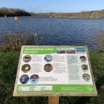 Photo of of a sign, with the lake in the background. The sign explains that the island in the view is a refuge for breeding birds such as Oystercatchers and Common terns.