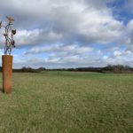 Photo of a tall metal sculpture. Curving rods carry 5 skylarks high into the sky.