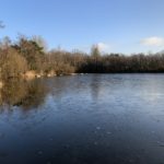 Photo of a frozen lake with warm winter sunshine catching the far side.
