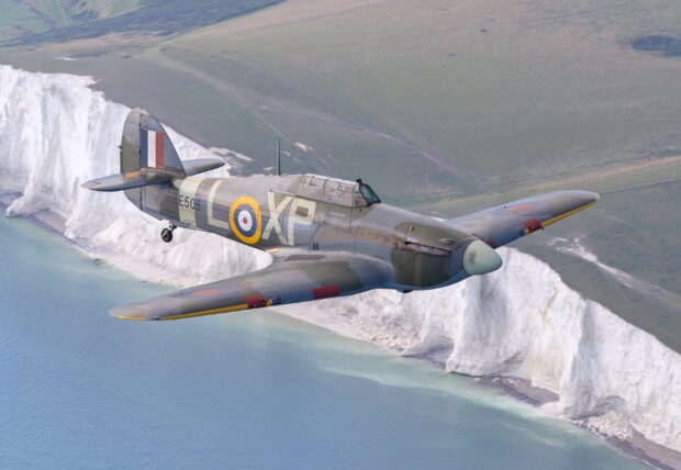 Photograph of a hurricane plane flying over white cliffs.