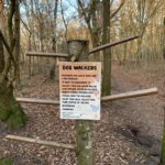 Photo of a post with branches for hanging poo bags on and a notice asking dog walkers to remember to collect their dog waste bags on the way back to the car park.