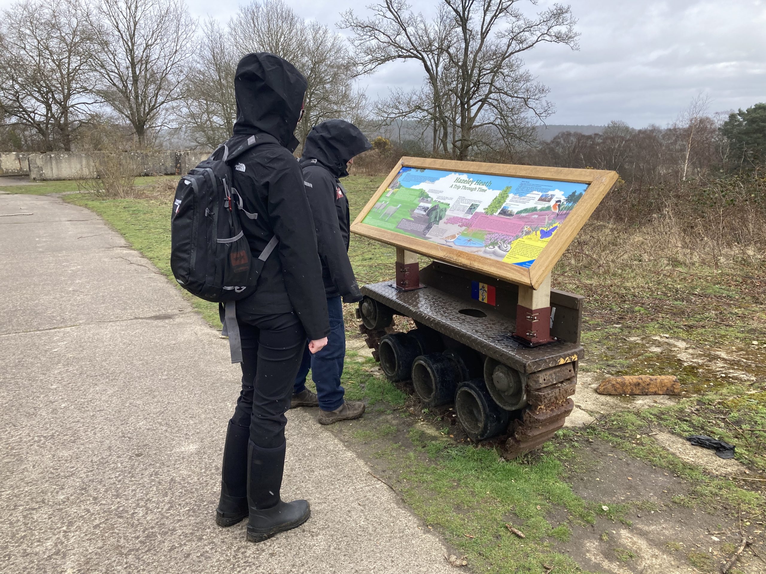 Photo of two of our wardens looking at an information panel mounted on a part of a tank track.