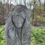 Photo of a wooden sculpture of a stylised person.