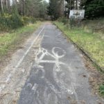 Photo of an old tarmac track with cycle lane symbols. And an old road sign. Relicts of transport lab work.