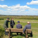 Photo of four men at a new bench, looking out at the magnificent view across the surrounding countryside.