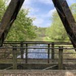 Photo of a canal, seen through the metal structure of a military bridge