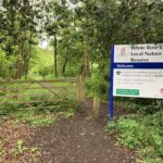 Photo of a gated entrance with a large Woking Borough Council sign saying "White Rose Lane Local Nature Reserve"