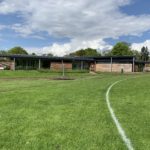 Photo of a green sports field in front of an attractive, low level modern building.