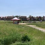 Photo of a gazebo positioned in a meadow. People are under the shade of the gazebo.