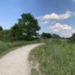 Photo of a surfaced path through a meadow and over a bridge.