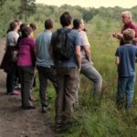 A photo taken at dusk, as people wait for Nightjars to start churring in the fading light. The group stand patiently listening to Steve.