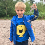 Photo of a small boy holding up an uncolied cardboard snake.