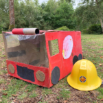 Photo of a cardboard fir engine. Made out of a box. A circle on the side of the box is the hose! Very cute!