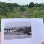 Photo of a black and white photograph showing tanks in a sandy landscape. One of the tanks is being winched by hand.