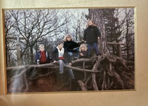 Photograph of Senior Warden Zoe as a child with family members, posing in front of large tree roots