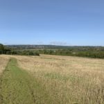 Photo taken on a hillside, looking down a grassy path and out over the surrounding countryside.