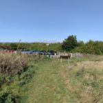 Photo taken looking towards a small cr park. There's an information board just outside the car park.