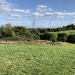 Photo of a view across a rolling countryside, with hedgerows and taller trees.