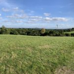 Photo of a green meadow, with a view across open countryside in the distance