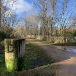 Photograph of a bluesky winter day. A concrete column stands beside the path, marked with a letter 'D'.