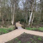 Photo shows a gravel path and a small bridge that connects Southwood Country Park to Southwood Woodland.