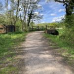 Photo looking down a surfaced path that goes past a pill box and over a bridge.