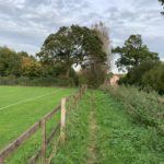 Photo of a rough, narrow path running down the side of a football pitch.