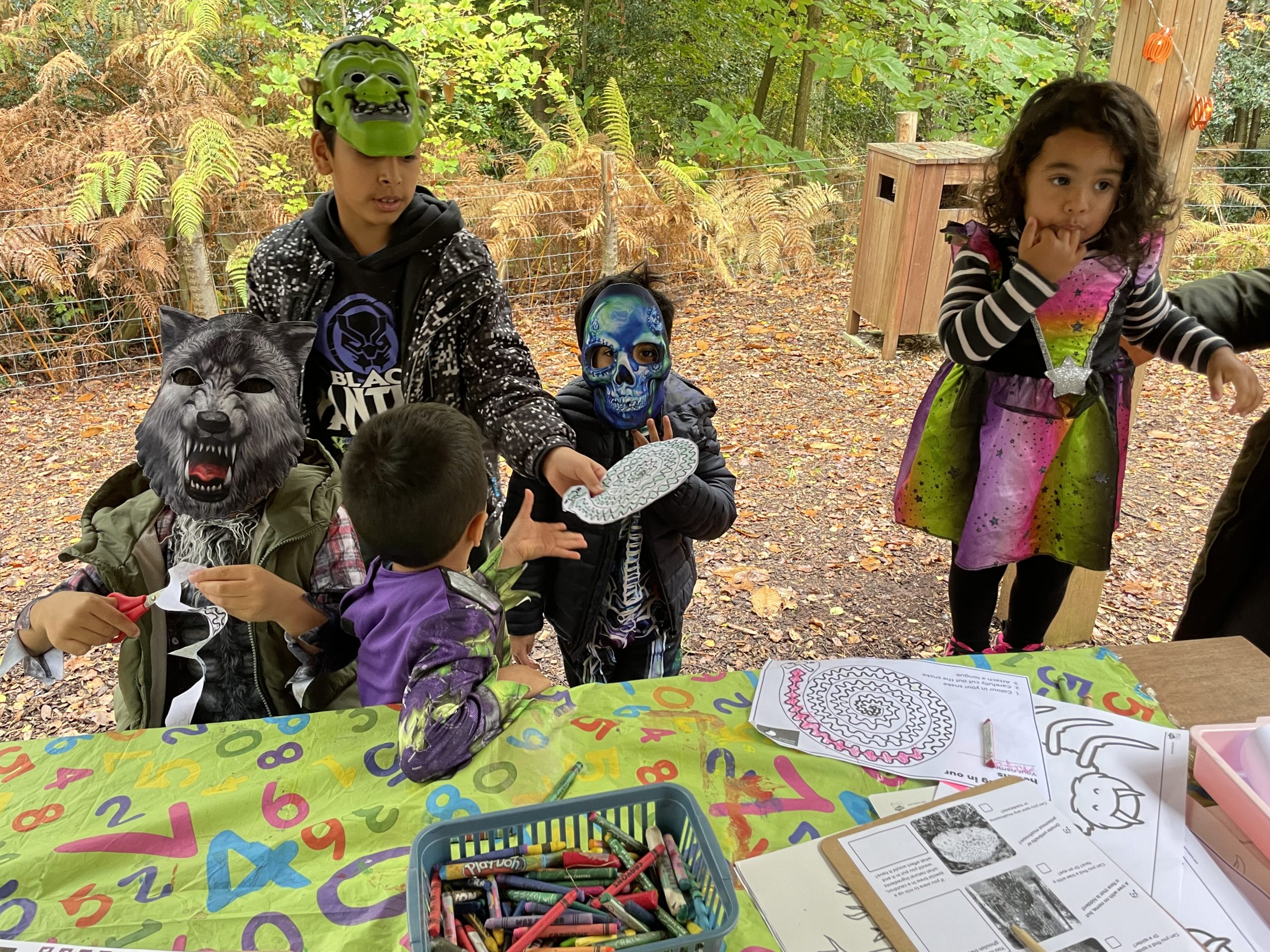 Photo of children dressed in Halloween constumes engaging in crafts on a heath