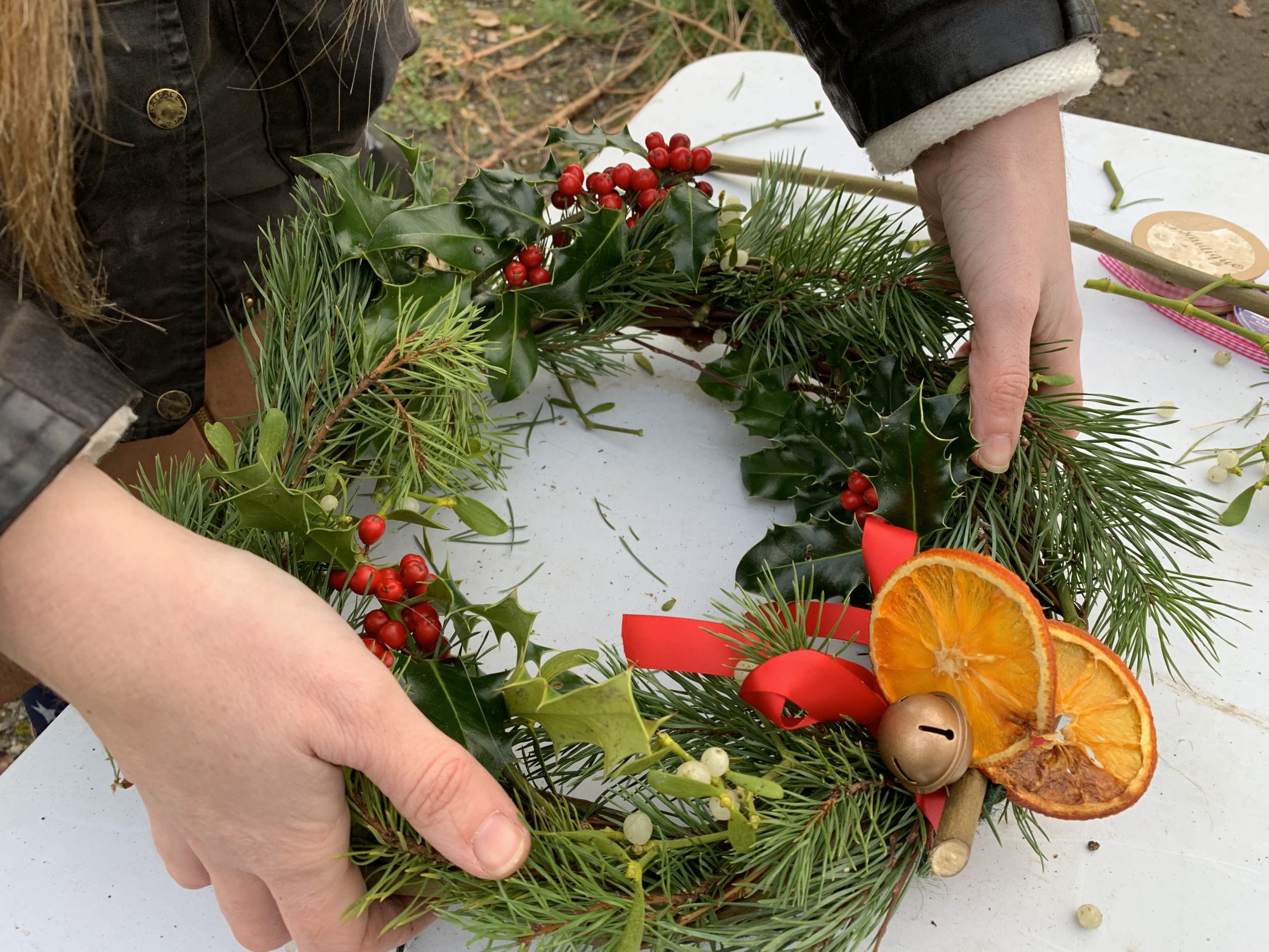 Photo of a christmas wreath made of pine with red ribbon and dried orange decorations